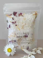 Miss Dior bath soak in a clear resealable pouch with white crystals and dried rose and calendula petals