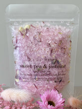 Sweet pea and jasmine bath soak in a clear resealable pouch with pastel pink crystals and dried floral botanicals