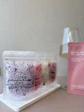 Black raspberry and vanilla bath soak in a clear pouch, displayed with other pastel bath soak pouches on a minimal tray